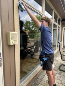professional cleaner wiping down residential windows on a patio in kansas city
